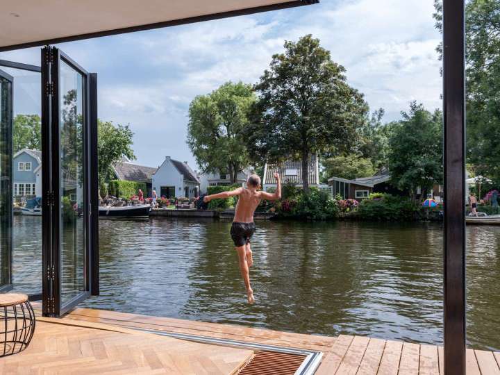 Junde springt durch geöffnete Glas-Faltwand in einen Fluss
