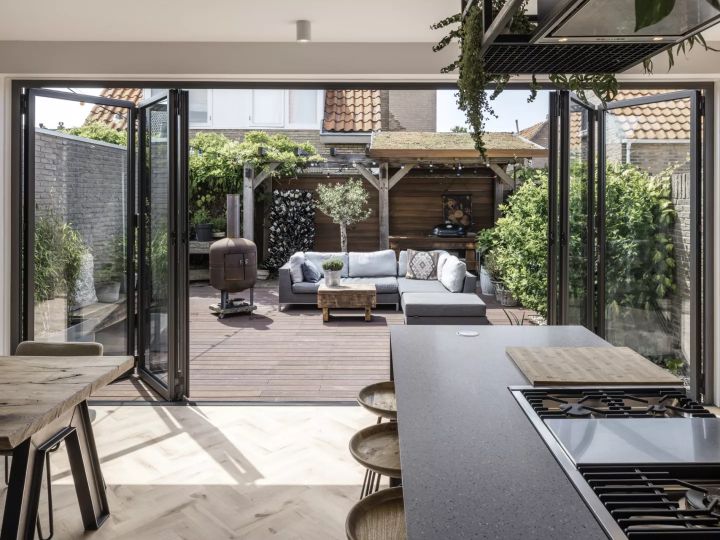 Die links und rechts jeweils miteinander verbundenen Elemente der Glas-Faltwand von Solarlux lassen sich einfach auffalten – und verwandeln den Wohn- und Essbereich in ein Outdoor-Wohnzimmer.  Copyright: Solarlux GmbH